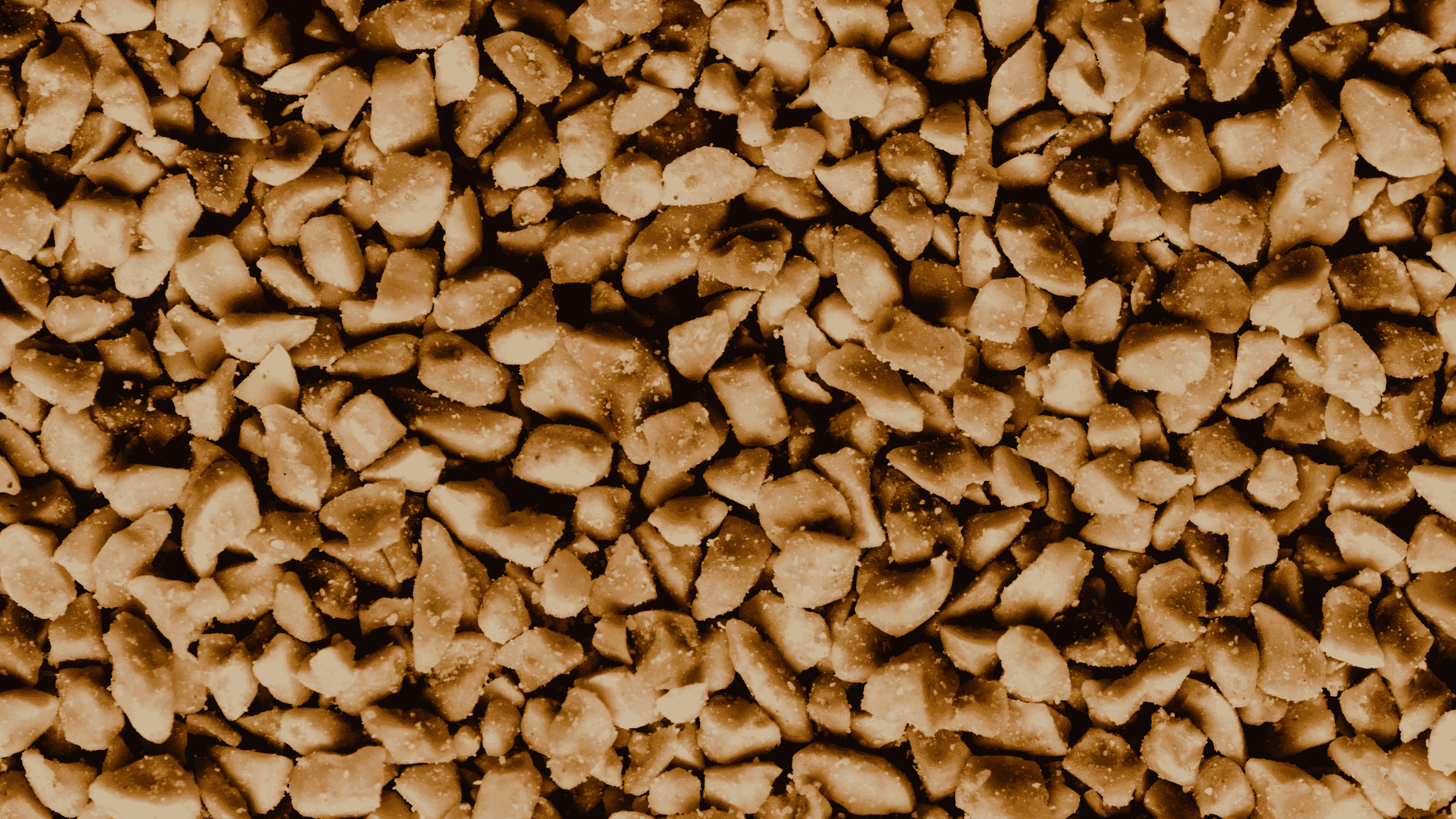 Detaliu cu arahide prăjite și sărate, tocate grosier. Textură clară, aspect apetisant – ideal pentru ilustrarea produselor din arahide sau a ingredientelor naturale.